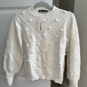 White sweater with pompons.